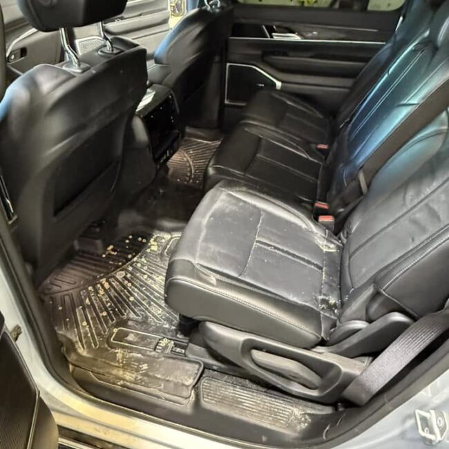 Dirty SUV back seat with sandy floor mats and soiled leather before interior detailing in Southwest Florida
