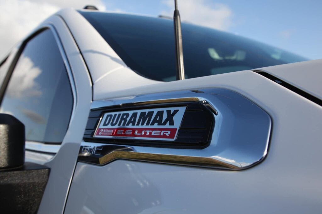 Close-up of a GMC Duramax hood emblem with glossy white paint and polished chrome after detailing in Southwest Florida