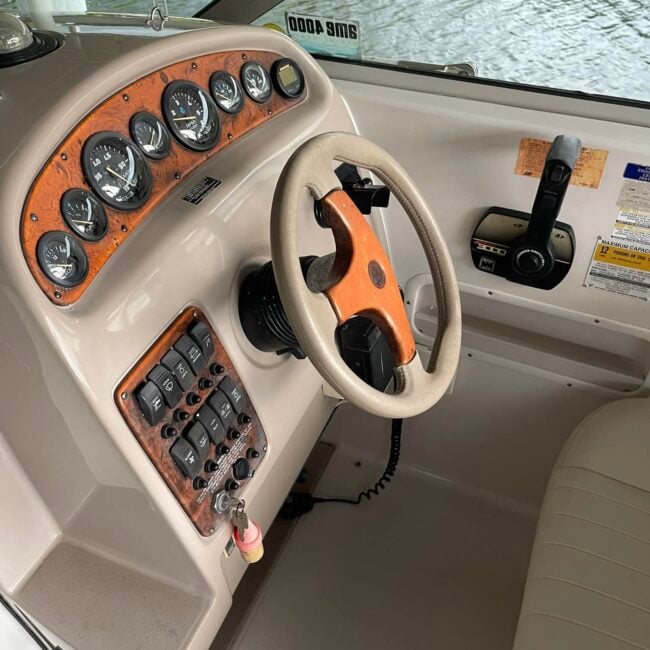 Clean cabin cruiser helm with restored tan upholstery and spotless dash after boat interior detailing in Southwest Florida