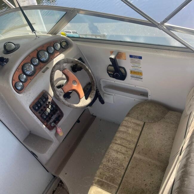 Dirty cabin cruiser helm with mildew-stained seats before boat interior detailing in Southwest Florida